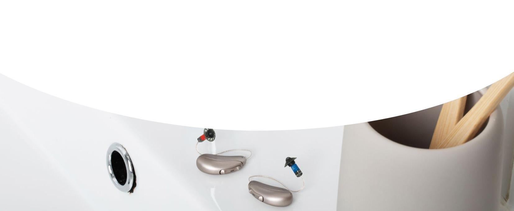 pair of hearing aids sitting on white sink next to toothbrush holder