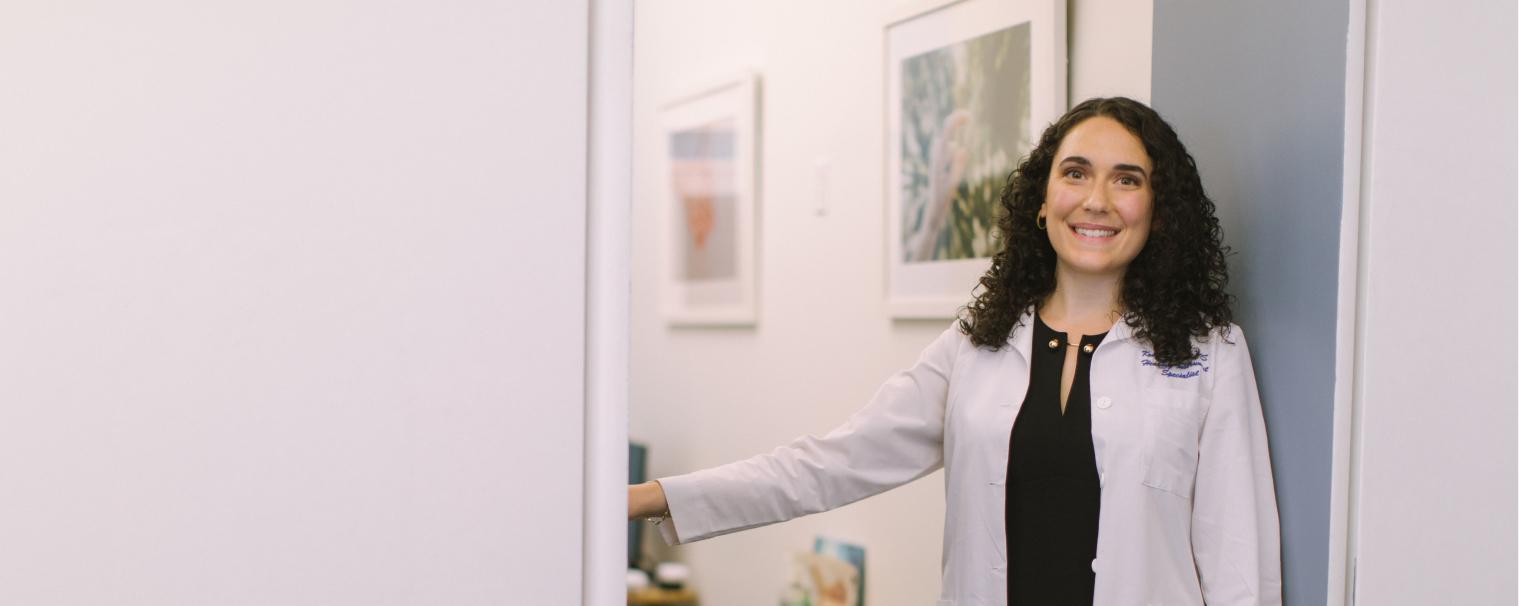 smiling female doctor wearing white coat standing in doorway