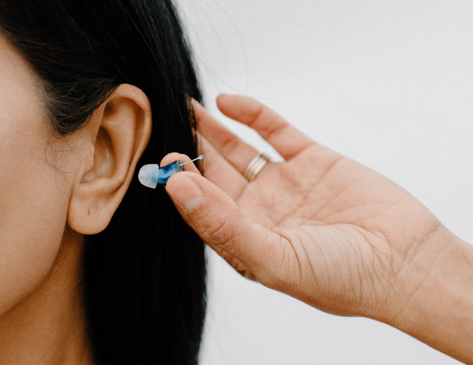 Woman holding small CIC hearing aid in hand