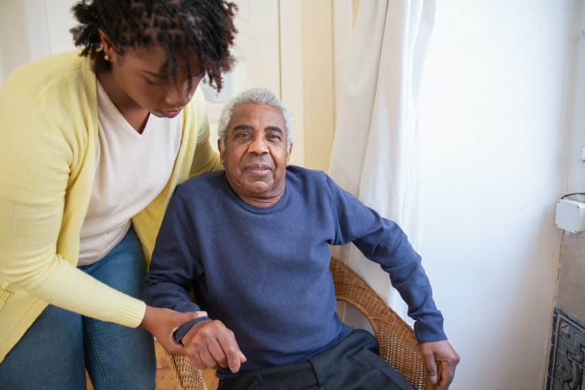 Woman helps elderly man in chair