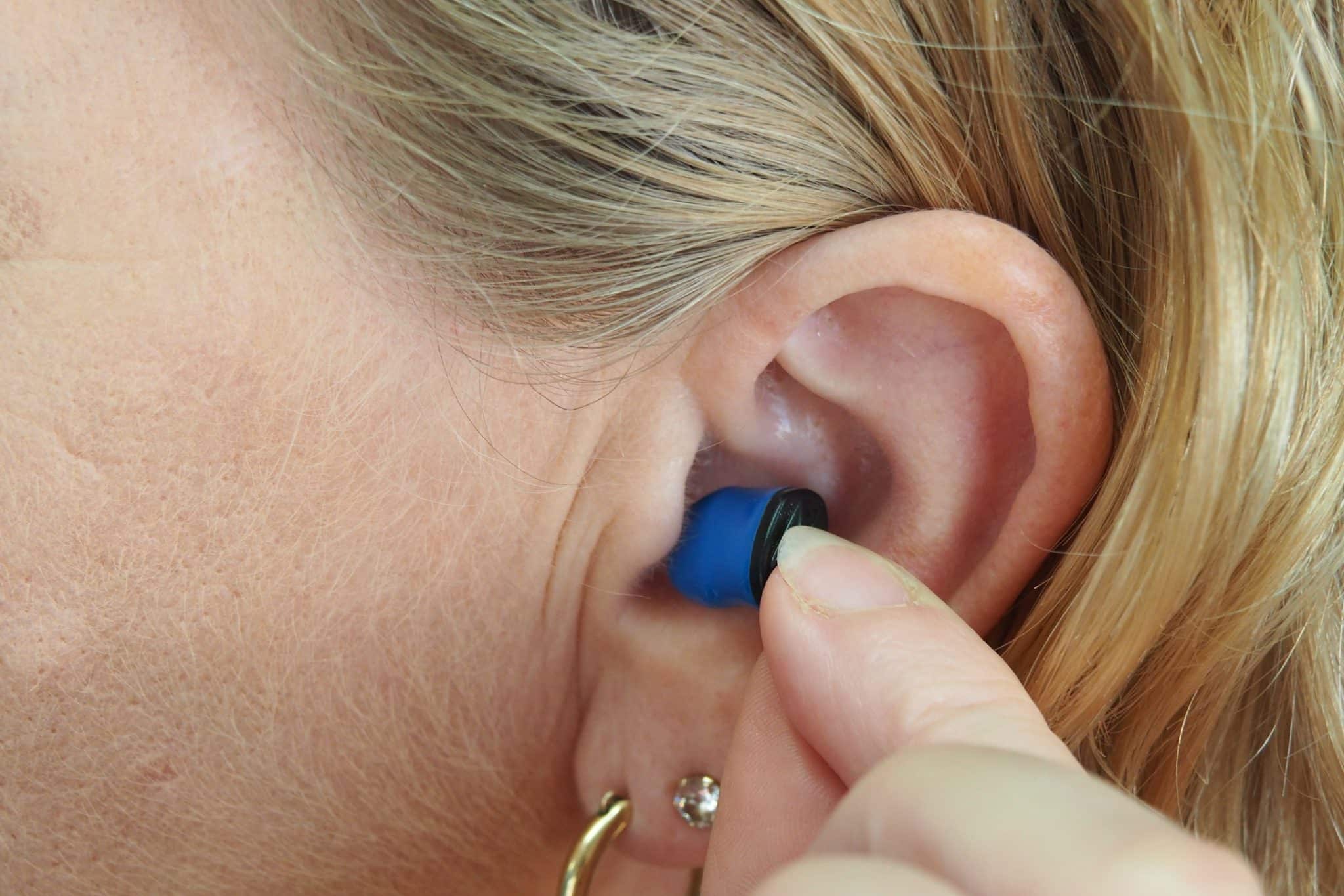 Girl placing small blue CIC hearing aid for sonic hearing aids banner